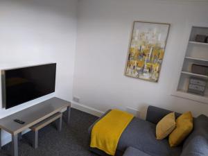 a living room with a couch and a flat screen tv at Glenclova - No 5 Bellyeoman, bright two bedroom apartment in Fife