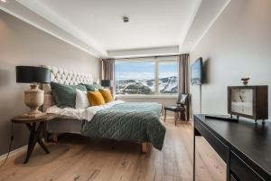 a bedroom with a bed and a desk and a window at Ustedalen Resort Leiligheter in Geilo