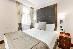a bedroom with a large bed with a large headboard at Gem Fitzrovia Hotel in London