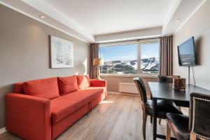 a living room with a red couch and a table at Ustedalen Resort Leiligheter in Geilo