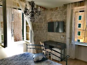 a bedroom with a desk and a tv on a wall at L&L Rooms Royal in Šibenik
