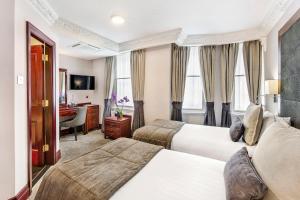 a hotel room with two beds and a desk at Gem Fitzrovia Hotel in London