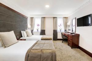 a hotel room with two beds and a desk at Gem Fitzrovia Hotel in London