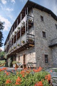 a large stone building with a balcony and flowers at Cascina Belvedì in Clanezzo