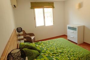 a bedroom with a bed and a dresser and a window at VILLA BUGANVILLA in Elche