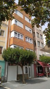 a tall building with a tree in front of it at Estudios Placeta dels Bous - Plaza Constitución in Benicarló