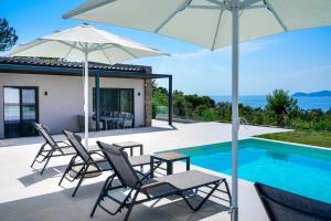 a patio with chairs and an umbrella next to a swimming pool at Videre Luxury Suites in Potos