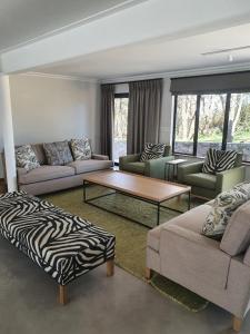 ein Wohnzimmer mit 2 Sofas und einem Couchtisch mit Zebramuster in der Unterkunft Via Lactea in Mmafefe