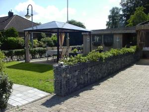 a garden with a stone wall and an umbrella at Ferienwohung Hanl - schöne FeWo mit 2 Schlafzimmern mit TV, Garten und großem Badezimmer in Wanderup