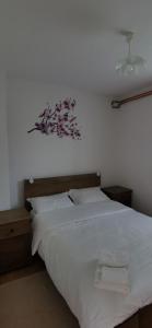 a bedroom with a white bed with a flower picture on the wall at APARTMAN DEDA in Rakovica