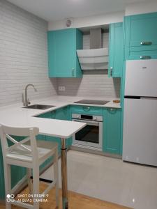 uma cozinha com armários azuis, um lavatório e uma mesa em El pisito de Lourizan em Pontevedra