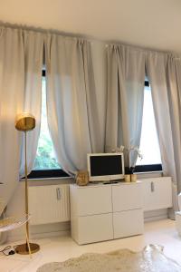 uma sala de estar com um computador numa cómoda em frente a uma janela em Shared a-partment • Möbliertes Zimmer in Köln - Ehrenfeld ! em Colônia