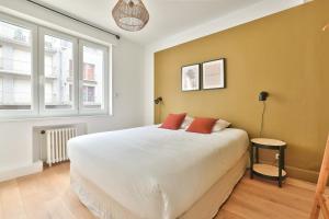 a bedroom with a large white bed with two red pillows at Appart Hypercentre in Lille