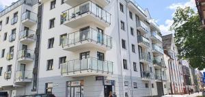 ein weißes Gebäude mit Balkon in einer Stadtstraße in der Unterkunft Apartement Insel Usedom Swinemünde in Świnoujście