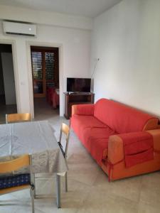 a living room with a red couch and a table at CASA GIOVANNA CASAL VELINO in Casal Velino