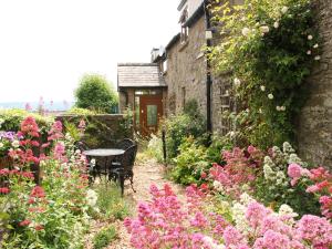 a garden with a table and some flowers at Linley Lane Cottage in Bishops Castle