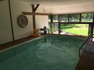 a swimming pool in a house with a clock on the wall at Le Moulin de l`Epinay in Sainte-Beuve-en-Rivière