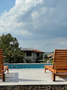 two wooden chairs sitting next to a swimming pool at Mutafova Guest House in Veliki Preslav