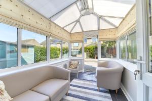 a conservatory with white furniture and windows at Host & Stay - Shorty's in Amble