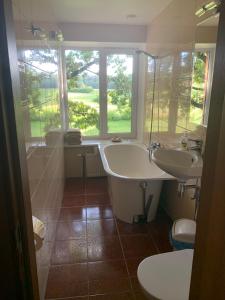 a bathroom with two sinks and a tub and a window at Pūteļkrogs in Tērvete