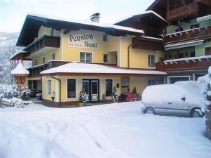 a building with a car parked in the snow at Pension Susi in Wagrain