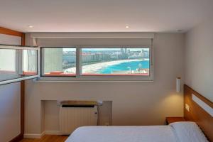 um quarto com uma janela com vista para o oceano em Orzan Beach 1 by TheBlueWaveApartments com em La Coruña