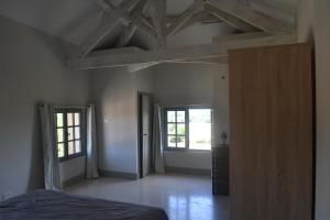 an empty room with a bed and two windows at domaine Les Castans in Saint-Thibéry