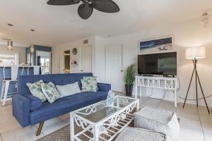 a living room with a blue couch and a tv at Sunset Views Steps From The Beach Duplex in Englewood
