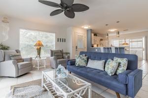 a living room with a blue couch and a ceiling fan at Sunset Views Steps From The Beach Duplex in Englewood
