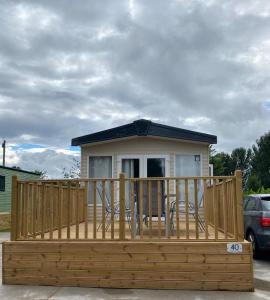 a mobile home with a deck and a house at Poppy Lodge in High Hesket