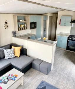 ein Wohnzimmer mit einem Sofa und einer Küche in der Unterkunft Poppy Lodge in High Hesket