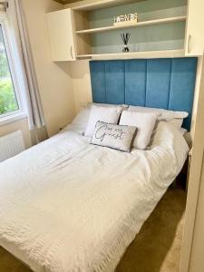 a bed with a blue headboard and a pillow on it at Poppy Lodge in High Hesket