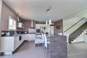 a kitchen with white cabinets and a kitchen island with chairs at Villa Design le Crès in Le Crès