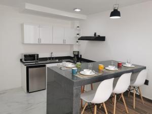 a kitchen with a counter with chairs and a table at Loft Estancia Real in Morelia