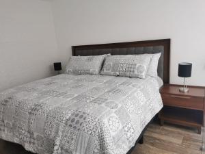 a bedroom with a bed with a gray and white comforter at Loft Estancia Real in Morelia