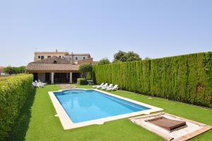 a swimming pool in a yard with a hedge at Villa Tofollubí 152 by Mallorca Charme in Llubí