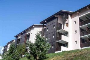 an apartment building with a tree in front of it at Petit appartement Labellisé Les 2 Alpes résidence Arc en Ciel télésiège Petite Aiguille in Les Deux Alpes