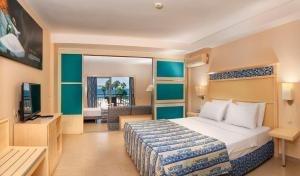 クシャダスにあるEphesia Holiday Beach Clubのベッドとテレビが備わるホテルルームです。