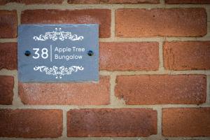 un signo de árbol de manzana en una pared de ladrillo en Apple Tree Bungalow, en Thornton