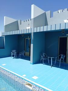 a swimming pool with chairs and a table next to a building at Shorfet Al Alamin Hotel in Al Ḩamrāʼ