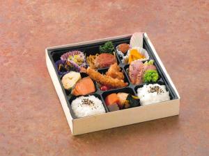 東京にあるアパホテル〈八丁堀 新富町〉のテーブルの上に寿司と野菜が詰まった箱
