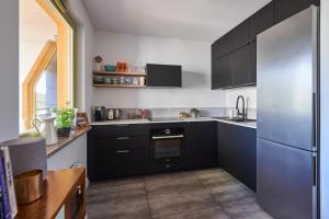a kitchen with black cabinets and a stainless steel refrigerator at Loved Up Sea Home in Sopot
