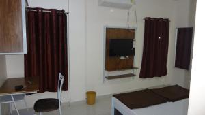 ナーグプルにあるAnand P G hostel males onlyのベッド、テレビ、カーテンが備わる客室です。