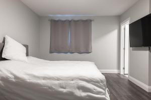 1 dormitorio con 1 cama blanca y TV en PRIVATE ROOM ENSUITE UPTOWN WATERLOO - e5, en Waterloo