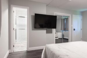1 dormitorio con TV de pantalla plana en la pared en PRIVATE ROOM ENSUITE UPTOWN WATERLOO - e5, en Waterloo