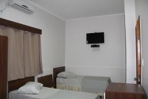 a room with two beds and a tv on the wall at Hotel Joia Fina in Aparecida