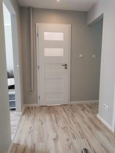 an empty room with a white door and wooden floors at Apartament Pionierska in Ustrzyki Dolne