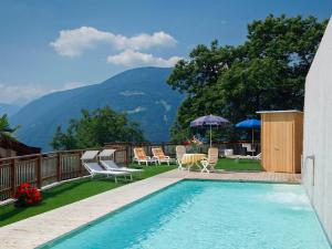 a swimming pool with chairs and a patio with mountains at Residence Innerfarmerhof in Tirolo