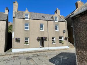 Forty Five, John Street, Stromness, في سترومنيس: مبنى من الطوب كبير مع علب الزهور على النوافذ