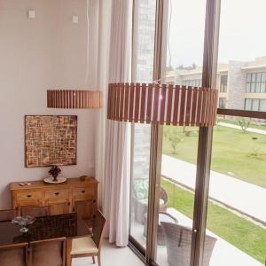 a living room with a table and a large window at Na Morada dos Milagres, condomínio Morada do Toque in São Miguel dos Milagres